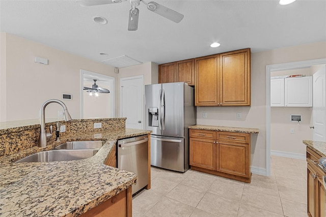 kitchen with ceiling fan, sink, stainless steel appliances, light stone counters, and light tile patterned floors