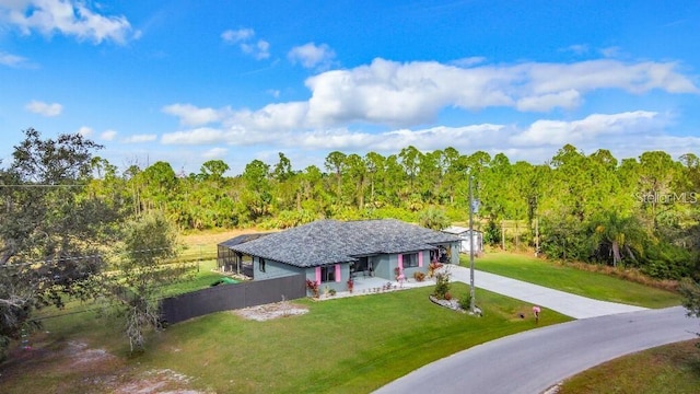 ranch-style home featuring glass enclosure and a front lawn