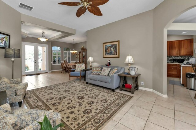 2388 Silver Palm Rd, North Port, FL 34288 - living room featuring arched walkways, light tile patterned floors, ceiling fan, french doors, and a raised ceiling