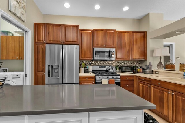 2388 Silver Palm Rd, North Port, FL 34288 - kitchen featuring appliances with stainless steel finishes, washer / clothes dryer, backsplash, brown cabinets, and recessed lighting
