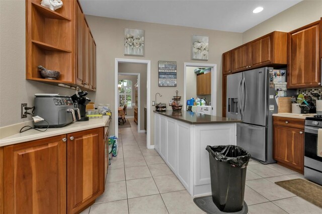 2388 Silver Palm Rd, North Port, FL 34288 - kitchen featuring appliances with stainless steel finishes, open shelves, light tile patterned floors, tasteful backsplash, and brown cabinets