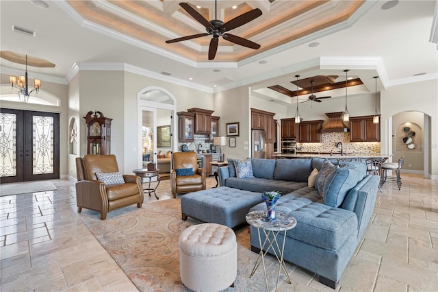 living room featuring sink, a tray ceiling, crown molding, french doors, and a towering ceiling