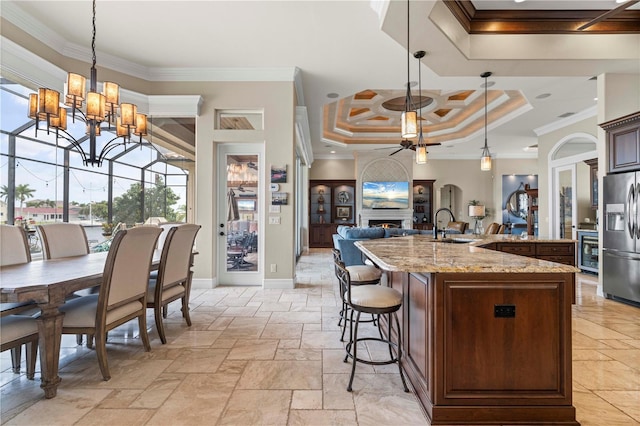 kitchen with hanging light fixtures, crown molding, and stainless steel fridge