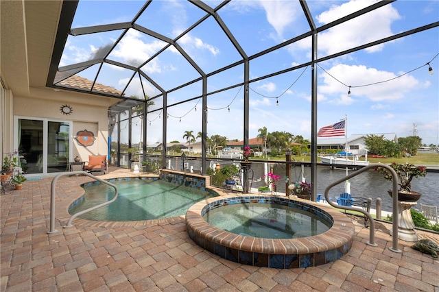 view of swimming pool with a lanai, a patio area, an in ground hot tub, and a water view