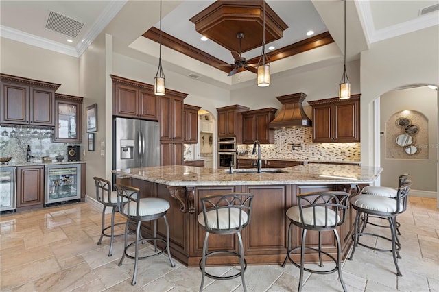 kitchen with sink, hanging light fixtures, beverage cooler, a spacious island, and custom exhaust hood