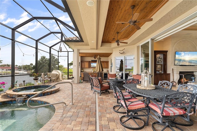 view of patio featuring ceiling fan, a pool with hot tub, a lanai, pool water feature, and a water view