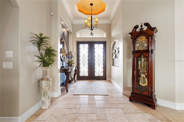 entrance foyer featuring french doors, ornamental molding, a notable chandelier, and a high ceiling