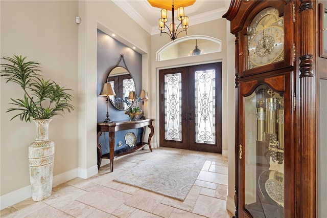 entryway with a chandelier, crown molding, and french doors