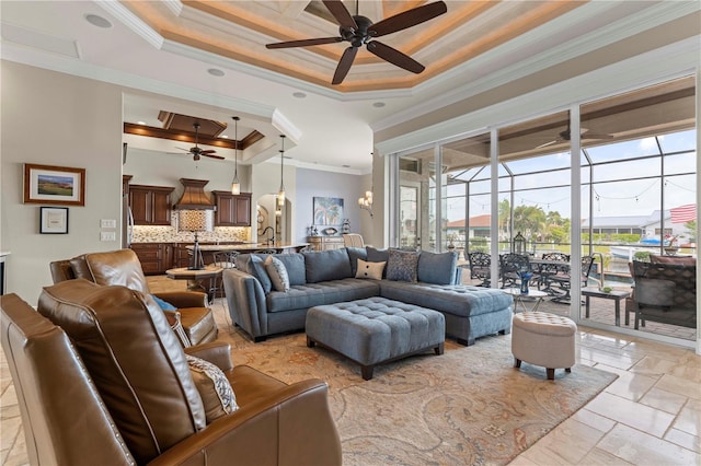 living room with a raised ceiling, crown molding, a towering ceiling, and ceiling fan