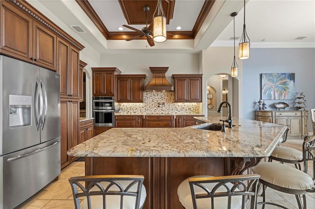 kitchen featuring custom range hood, stainless steel appliances, sink, decorative light fixtures, and a large island