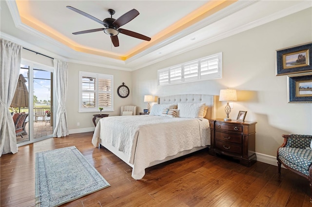 bedroom with access to outside, hardwood / wood-style flooring, ceiling fan, and a tray ceiling