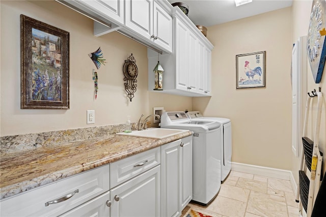 washroom with cabinets, washing machine and dryer, and sink