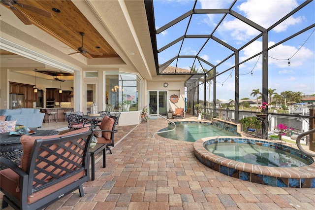 view of swimming pool with a water view, a patio, a lanai, ceiling fan, and an in ground hot tub