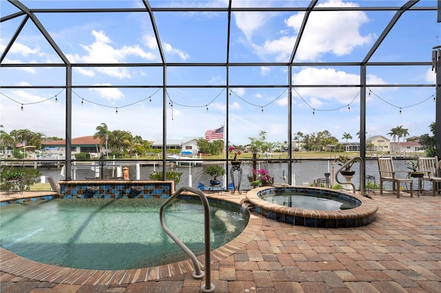 view of pool with glass enclosure, a water view, an in ground hot tub, and a patio area