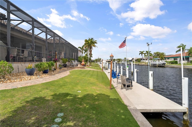 dock area with a lanai, a yard, and a water view