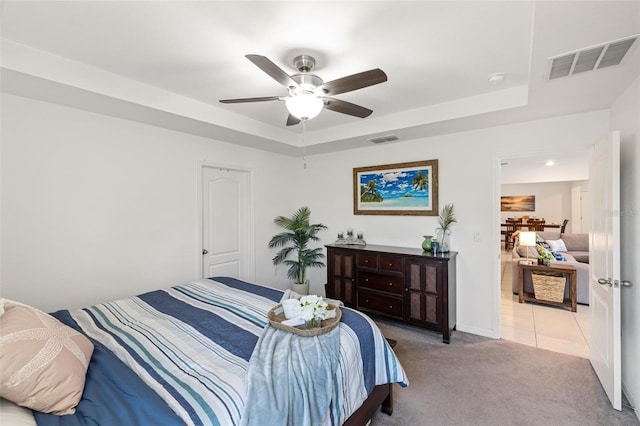 carpeted bedroom featuring ceiling fan and a tray ceiling