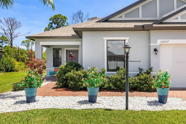 view of exterior entry featuring a garage and a yard