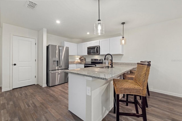 kitchen featuring white cabinetry, appliances with stainless steel finishes, dark hardwood / wood-style floors, a breakfast bar area, and kitchen peninsula