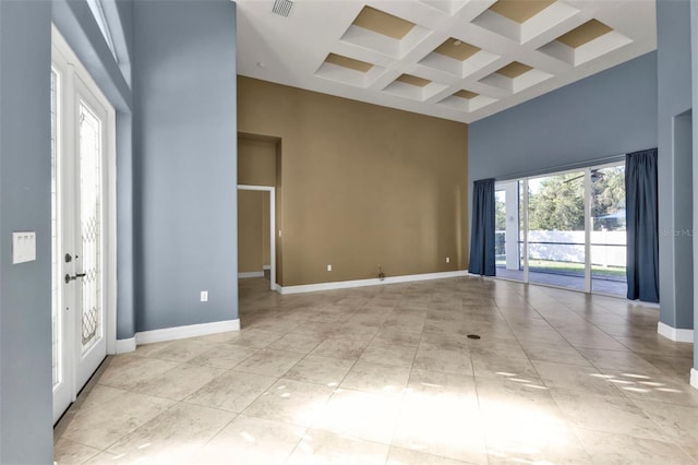 tiled empty room featuring coffered ceiling, a towering ceiling, and beam ceiling