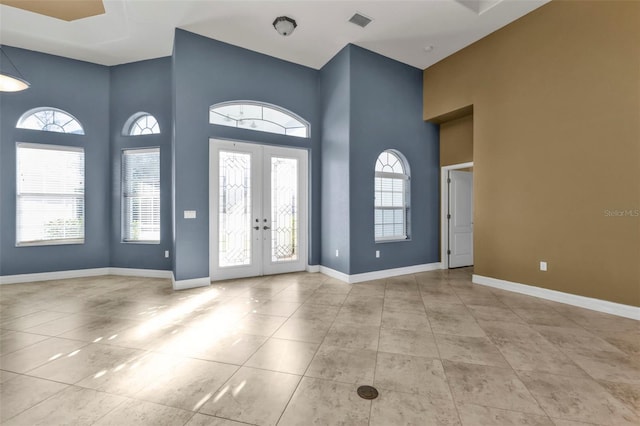 foyer entrance with a towering ceiling, light tile patterned floors, and french doors