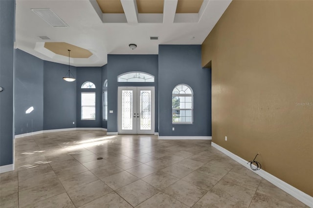 tiled entrance foyer featuring a tray ceiling, a towering ceiling, and french doors