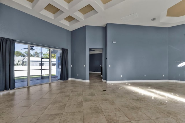 empty room with a towering ceiling, coffered ceiling, beam ceiling, and light tile patterned floors