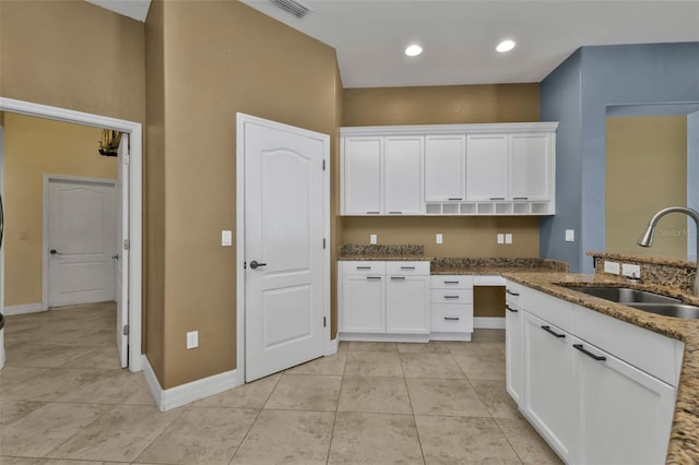 kitchen with stone countertops, sink, and white cabinets