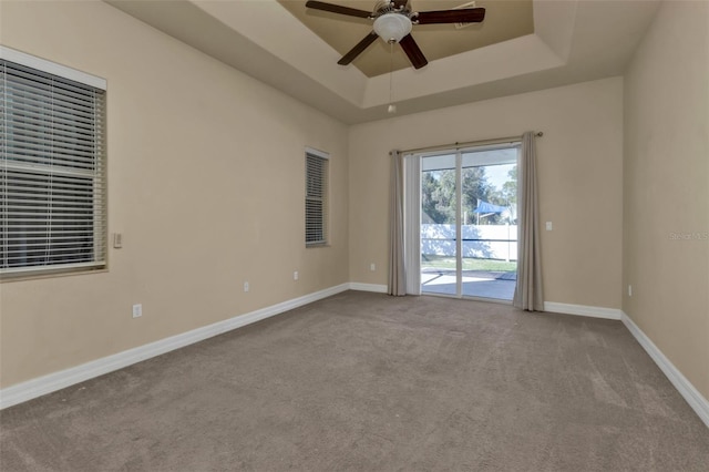 carpeted empty room featuring a tray ceiling and ceiling fan