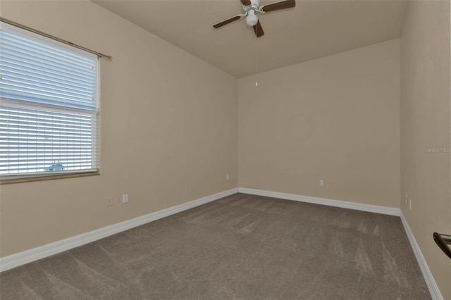 empty room with dark colored carpet, baseboards, ceiling fan, and vaulted ceiling