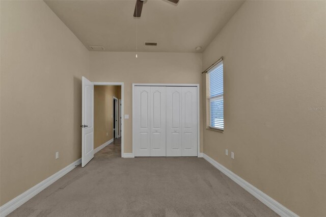 unfurnished bedroom featuring light carpet, a closet, and ceiling fan