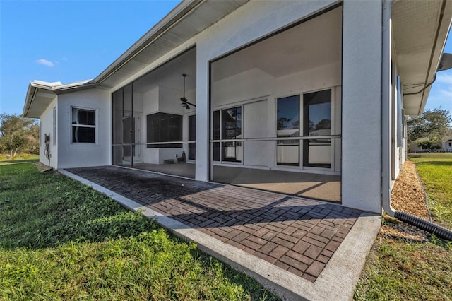 exterior space featuring a lawn, a sunroom, and stucco siding