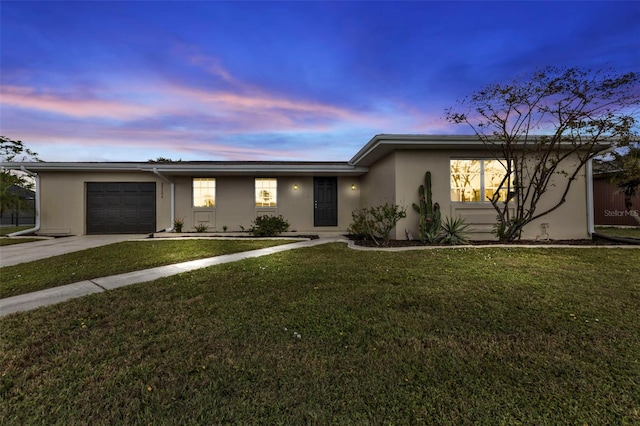 ranch-style home featuring a garage and a yard