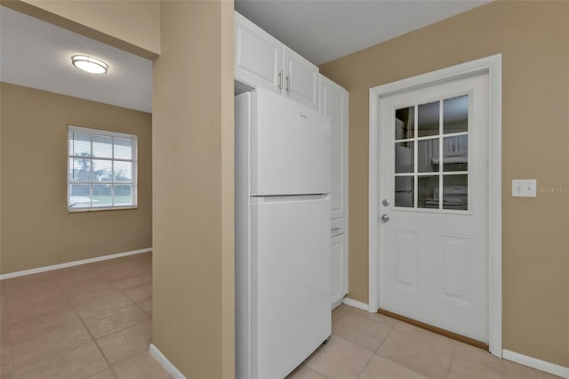 kitchen featuring white cabinetry, white refrigerator, and light tile patterned flooring