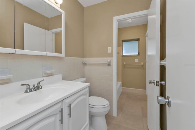 bathroom with toilet, tile walls, tile patterned flooring, vanity, and a tub to relax in