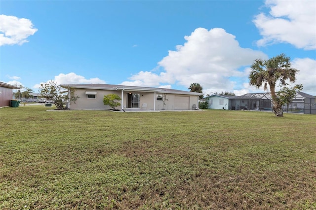 rear view of property with a garage, a lawn, and a lanai