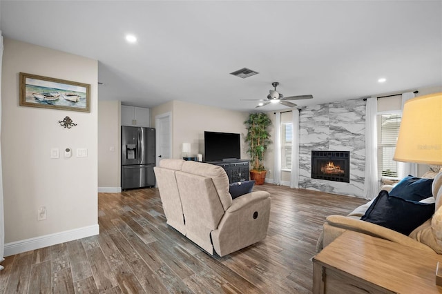 living room featuring dark hardwood / wood-style flooring, ceiling fan, and a fireplace