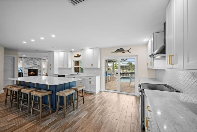 kitchen with wood-type flooring, a center island, stainless steel range with electric stovetop, a kitchen breakfast bar, and white cabinetry