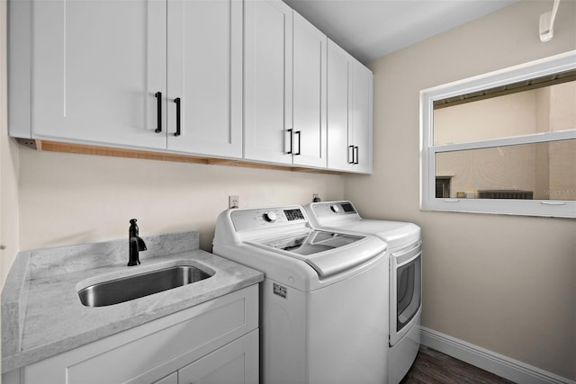 laundry room with cabinets, washer and clothes dryer, sink, and dark hardwood / wood-style flooring