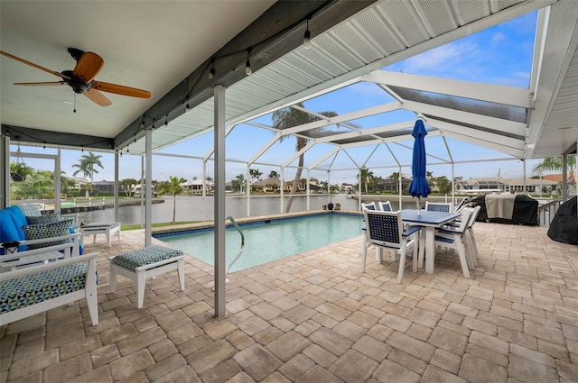 view of swimming pool featuring a patio area, a water view, a lanai, and ceiling fan