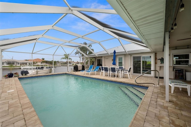 view of swimming pool with glass enclosure, a patio, and a water view