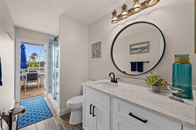 bathroom with hardwood / wood-style flooring, vanity, toilet, and walk in shower