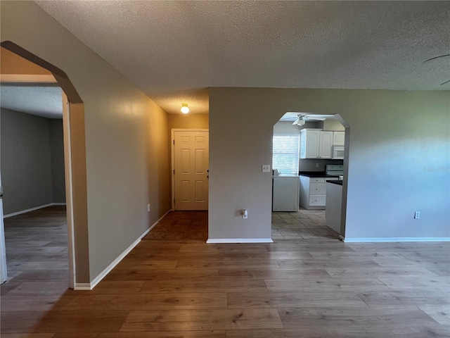 unfurnished room with light hardwood / wood-style floors, ceiling fan, and a textured ceiling