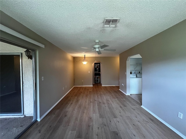 spare room featuring ceiling fan, wood-type flooring, a textured ceiling, and washer / clothes dryer