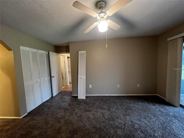 unfurnished bedroom with a textured ceiling, dark colored carpet, and ceiling fan