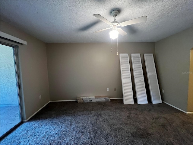 unfurnished bedroom featuring a textured ceiling, ceiling fan, and dark carpet