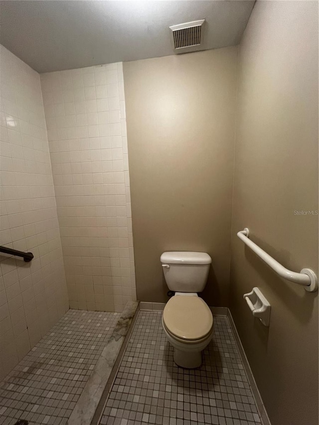 bathroom featuring toilet, tile patterned flooring, and a tile shower