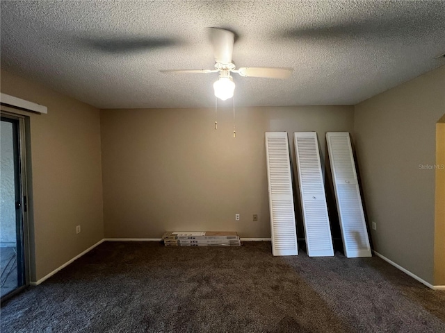 unfurnished bedroom with ceiling fan, a textured ceiling, and dark colored carpet