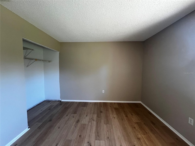 unfurnished bedroom with dark wood-type flooring, a textured ceiling, and a closet