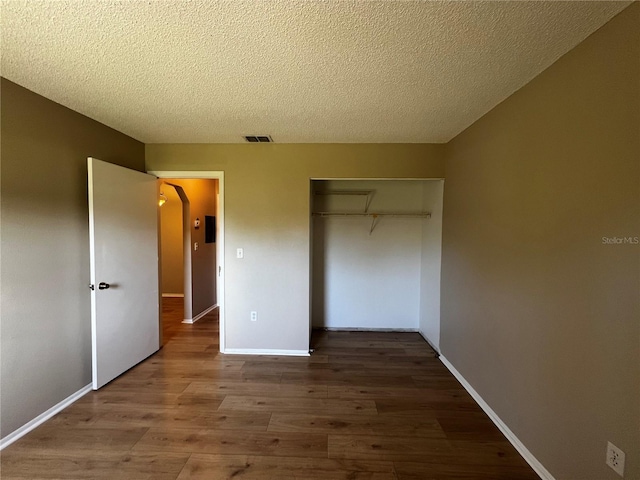 unfurnished bedroom featuring a closet, wood-type flooring, and a textured ceiling