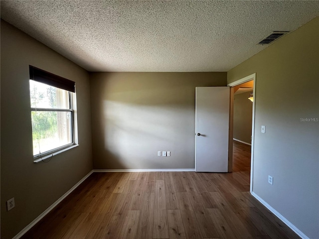 unfurnished room featuring wood-type flooring and a textured ceiling